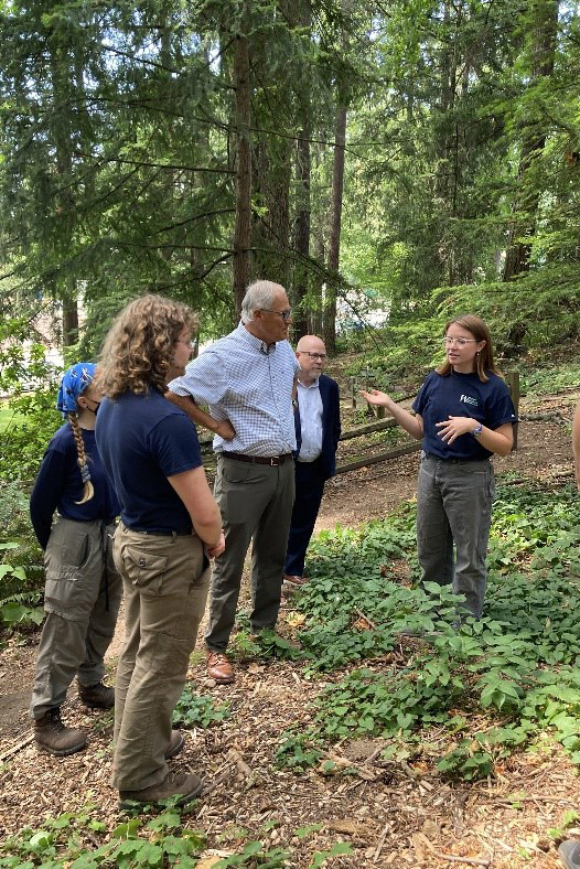 Gov. Inslee stands in a forest with a WCC crew and listens to a member.